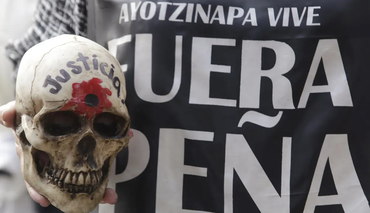 Demonstran  memegang tengkorak saat pawai peringatan 14 bulan hilangnya mahasiswa Universitas Ayotzinapa Raul Isidro Burgos di Mexico City, Meksiko, (26/11). Demonstran turun kejalan untuk menuntut keadilan 43 siswa yang hilang. (REUTERS/Daniel Becerril)