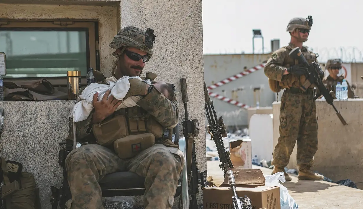 Seorang Marinir yang ditugaskan ke Unit Ekspedisi Marinir (MEU) ke-24 menenangkan seorang bayi selama evakuasi di Bandara Internasional Hamid Karzai, di Kabul, Afghanistan, Jumat (20/8/2021).  (Sgt. Isaiah Campbell/U.S. Marine Corps via AP)