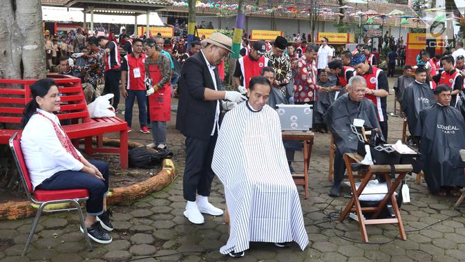 Presiden Joko Widodo disaksikan Ibu Negara Iriana saat mengikuti acara cukur rambut massal di Garut, Jawa Barat, Sabtu (19/1). Dalam acara cukur rambut massal ini, rambut Jokowi dicukur oleh tukang cukur langganannya, Herman. (Liputan6.com/Angga Yuniar)