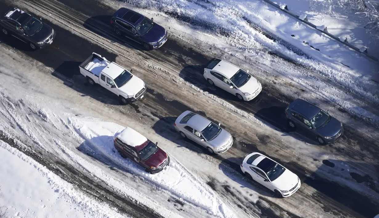 Lalu lintas perlahan bergerak di sekitar mobil yang terdampar di bagian Interstate 95 di Quantico, Virginia, Selasa (4/1/2022). Salju tebal menimbulkan kekacauan di Washington, DC, menyebabkan ratusan pengemudi terdampar di jalan raya utama di Virginia. (AP Photo/Steve Helber)