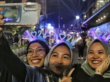Warga berswafoto saat perayaan malam pergantian tahun di kawasan Jalan MH Thamrin, Jakarta Minggu (31/12/2023). (Liputan6.com/Angga Yuniar)