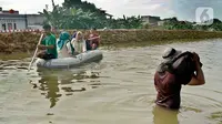 Warga menggunakan perahu karet melintasi banjir yang melanda Perumahan Total Persada, Periuk, Kota Tangerang, Selasa (4/2/2020). Banjir akibat tanggul kali Ledug jebol membuat ratusan rumah di Total Persada terendam banjir hingga mencapai 3,5 meter. (merdeka.com/Arie Basuki)