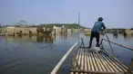 Seorang pria mengendalikan rakit bambunya di kawasan Bendungan Karian yang mengering di Kampung Somang, Lebak, Banten, Kamis (30/7/2026). (AFP/ Bay Ismoyo)