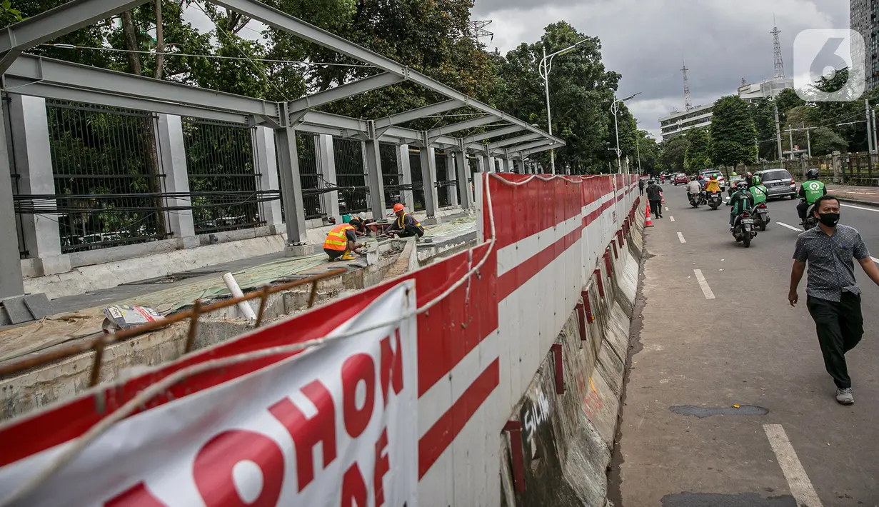 Warga berjalan melintasi proyek pembangunan selter di kawasan Stasiun Palmerah, Jakarta, Selasa (2/2/2021). Penataan ini diharapkan bisa menjadi solusi kemacetan yang kerap terjadi di kawasan tersebut. (Liputan6.com/Faizal Fanani)