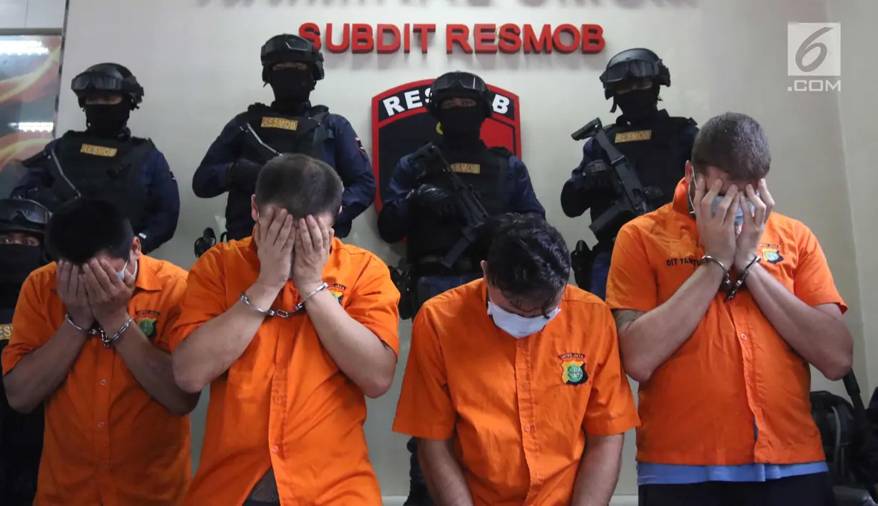 Empat WNA tersangka menutupi wajah saat pengungkapan tiga kasus pencurian data elektronik (Skimming) di Polda Metro Jaya, Jakarta, Selasa (4/3). Empat tersangka tersebut berhasil diamankan Ditreskrimum Polda Metro Jaya. (Liputan6.com/Arya Manggala)