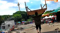 Seorang pedagang memindahkan barang ke tempat penampungan sementara di kawasan Kandang Rusa Monas, Jakarta, Selasa (22/4/14). (Liputan6.com/Miftahul Hayat)