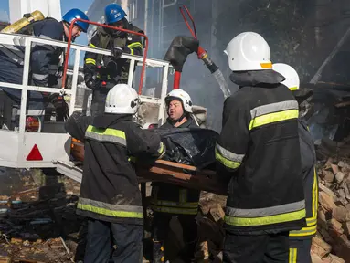 Petugas pemadam kebakaran membawa mayat seorang pria yang tewas setelah sebuah pesawat tak berawak menghantam gedung-gedung di Kyiv, Ukraina, Senin (17/10/2022). Pesawat tak berawak menghantam sejumlah gedung ibu kota Ukraina pada Senin pagi ledakan tesebut menggema di seluruh Kyiv dan menimbulkan kepanikan sehingga orang-orang berlarian ke lokasi yang aman. (AP Photo/Roman Hrytsyna)