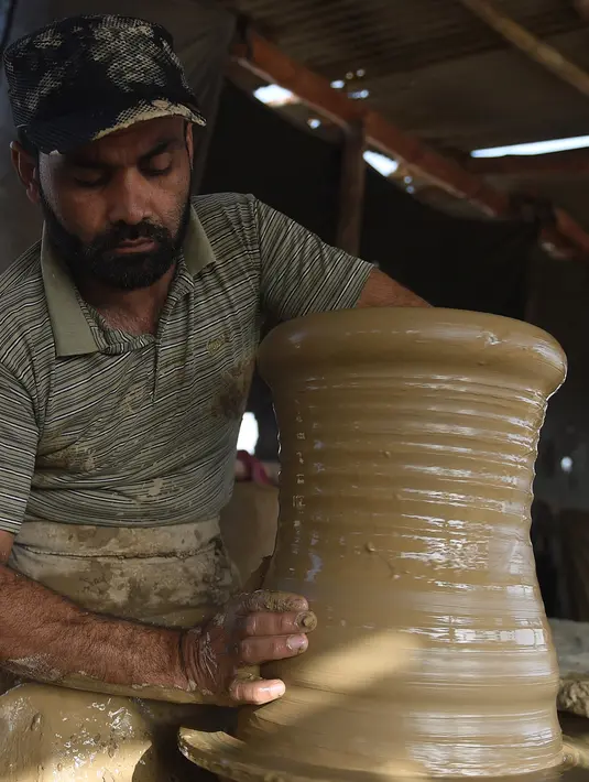 Seorang pembuat tembikar membuat pot tanah liat di sebuah bengkel di Karachi, Pakistan, Rabu (23/2/2022). (Rizwan TABASSUM/AFP)