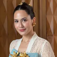 Pevita Pearce tampil memesona mengenakan atasan kebaya brokat putih lengan panjang sebagai inner dipadukan buister warna biru yang dihiasi bros besar serasi dengan anting-anting dan hiasan rambutnya. [ @pevpearce]
