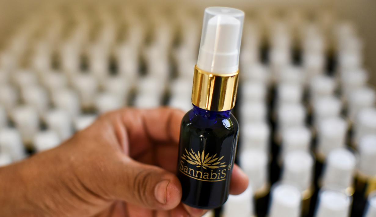 Pekerja saat menunjukkan kemasan yang berisi ekstrak ganja yang digunanakan untuk kegiatan seksualitas wanita di laboratorium, Toez, Cauca, Kolombia, (13/7). Cara penggunaanya disemprotkan ke bagian intim wanita.(LUIS ROBAYO / AFP)