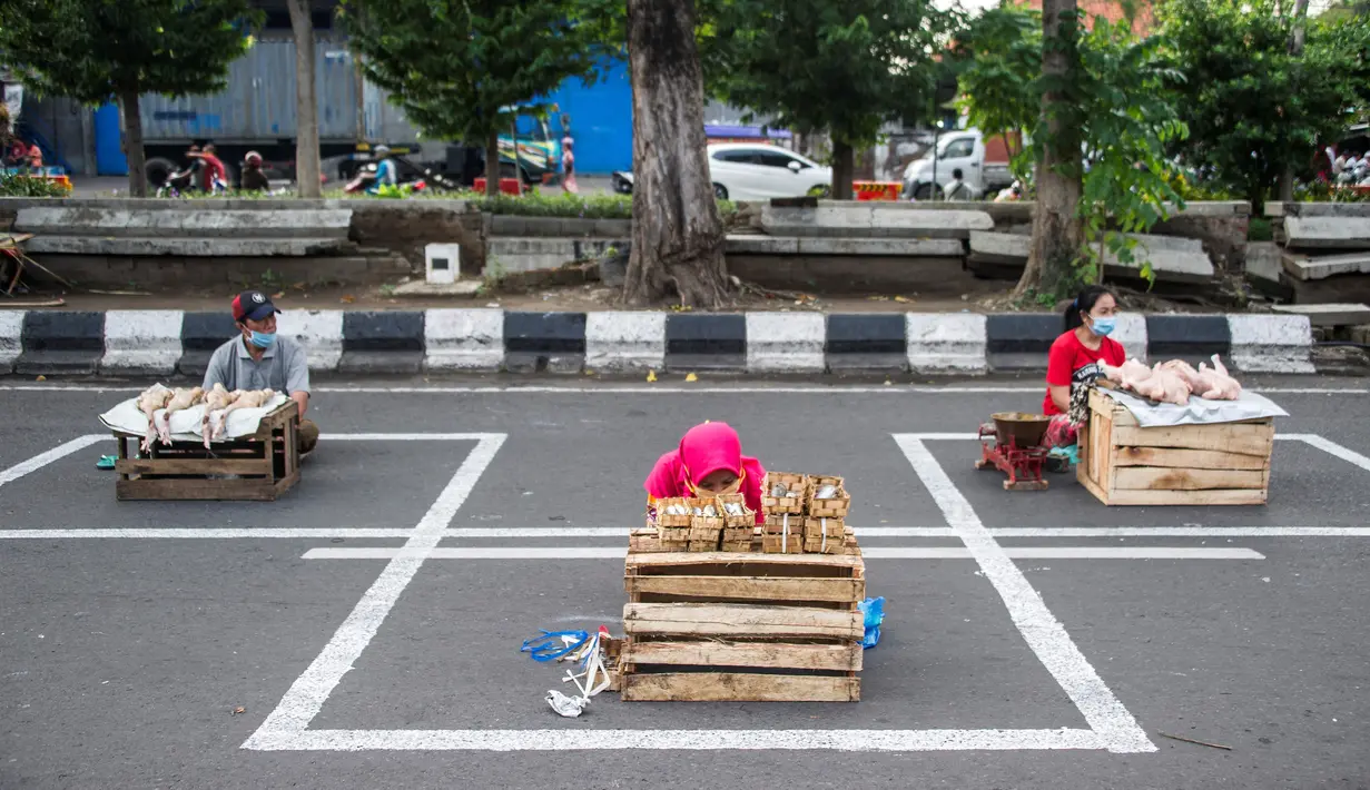 Pedagang menjual dagangannya di antara petak-petak untuk menerapkan jaga jarak (physical distancing) di sepanjang jalan di Surabaya, Selasa (2/6/2020). Garis petak-petak bagi pedagang itu sebagai langkah pencegahan penyebaran COVID-19. (Photo by Juni Kriswanto / AFP)