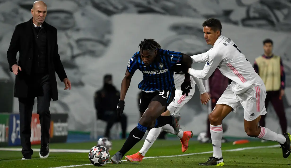 Penyerang Atalanta, Duvan Zapata bersaing dengan bek Real Madrid, Raphael Varane Pasalic  pada leg kedua babak 16 besar Liga Champions di Estadio Alfredo di Stefano, Rabu (17/3/2021) dini hari WIB. Real Madrid menang 3-1 dan lolos ke perempat final dengan agregat 4-1. (PIERRE-PHILIPPE MARCOU/AFP)