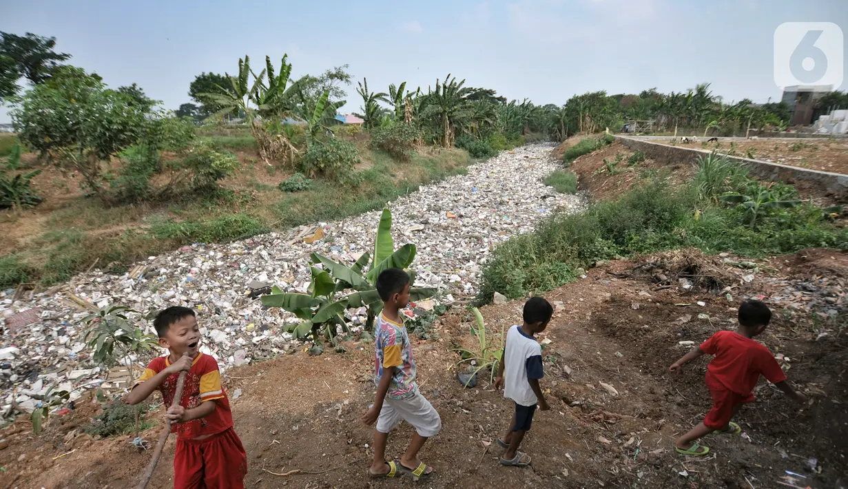 Anak-anak bermain dekat tumpukan sampah yang memenuhi Kali Jambe, Desa Satria Jaya, Tambun Utara, Bekasi, Jawa Barat, Kamis (31/10/2019). Sampah tersebut memenuhi aliran Kali Jambe akibat terbawa arus saat hujan mengguyur sejumlah wilayah di Kabupaten Bekasi. (merdeka.com/Iqbal Nugroho)