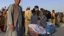 Seorang pria Afghanistan bersiap untuk mendorong gerobak dorong dengan barang-barang makanan yang didistribusikan oleh organisasi Kristen yang berbasis di Islamabad di pinggiran Chaman, sebuah kota perbatasan di provinsi Baluchistan barat daya Pakistan, Selasa (31/8/2021). (AP Photo)