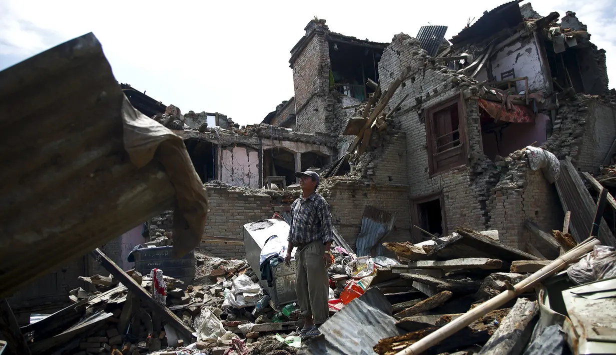 Seorang pria berdiri di puing-puing bangunan setelah gempa susulan berkekuatan 7,3 SR melanda Sankhu, Nepal, Selasa (12/5/2015). Sebelumnya, luka atas gempa dahsyat yang terjadi 25 April lalu di Nepal masih belum terobati. (REUTERS/Navesh Chitrakar)
