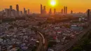 Rangkaian kereta melewati kawasan padat penduduk dengan latar belakang gedung bertingkat saat matahari terbenam di kawasan Manggarai, Jakarta, Kamis, 16/07/ 2026. (KLY/ Arie Basuki)