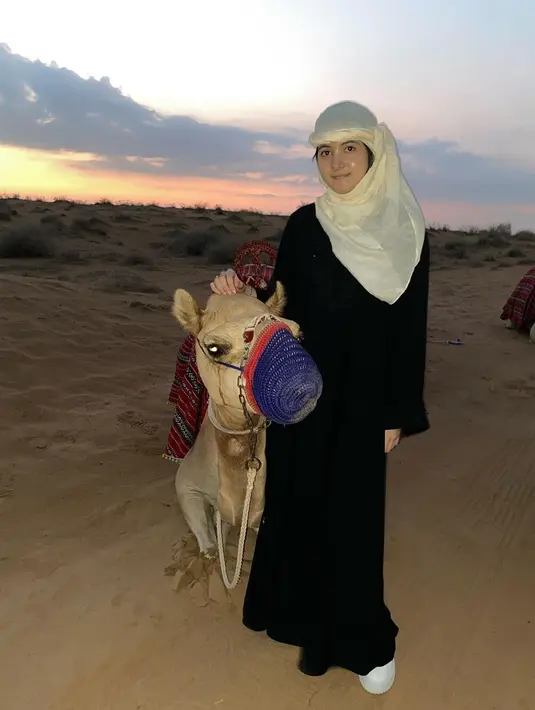 Banyak penggemar yang terpesona dengan paras manis Bulan Sutena. Di momen liburan tersebut, pelantun lagu 'Tetap Punyaku' itu tampil dengan hijab kuning bergaya khas perempuan Arab. Dengan memakai busana panjang berwarna hitam, Bulan tampak enjoy saat berpose bersama dengan unta di sebelahnya. (Liputan6.com/IG/@bulansutena)