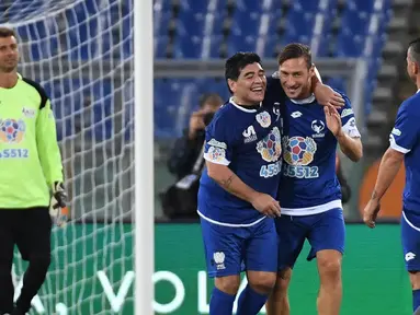 Dua legenda sepak bola, Francesco Totti (tengah) dan Diego Maradona saling merangkul pada laga amal bertajuk 'United for Peace', di Stadion Olimpico, Roma, Kamis (13/10/2016) dini hari WIB. (EPA/Alessandro Di Meo)