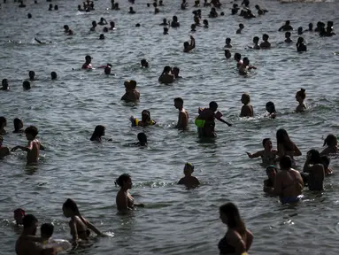 Orang-orang mendinginkan diri di pantai di Barcelona, ​​​​Spanyol, Rabu, 12 Juli 2023. (AP Photo/Emilio Morenatti)