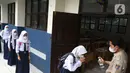 Siswi memberi salam kepada guru sebelum mengikuti Pembelajaran Tatap Muka Terbatas (PTMT) di SMPN 1 Depok, Depok, Jawa Barat, Senin (4/10/2021). PTMT diberlakukan dengan protokol kesehatan dan pembelajaran hanya dilakukan seminggu dua kali selama dua jam. (Liputan6.com/Herman Zakharia)