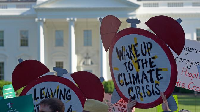 Demonstran membawa poster saat aksi di dekat Gedung Putih di Washington, AS, Kamis (1/6). Demonstran memprotes keputusan Donald Trump yang menarik AS dari perjanjian Paris tentang perubahan iklim yang disepakati pada 2015. (AP/ Susan Walsh)