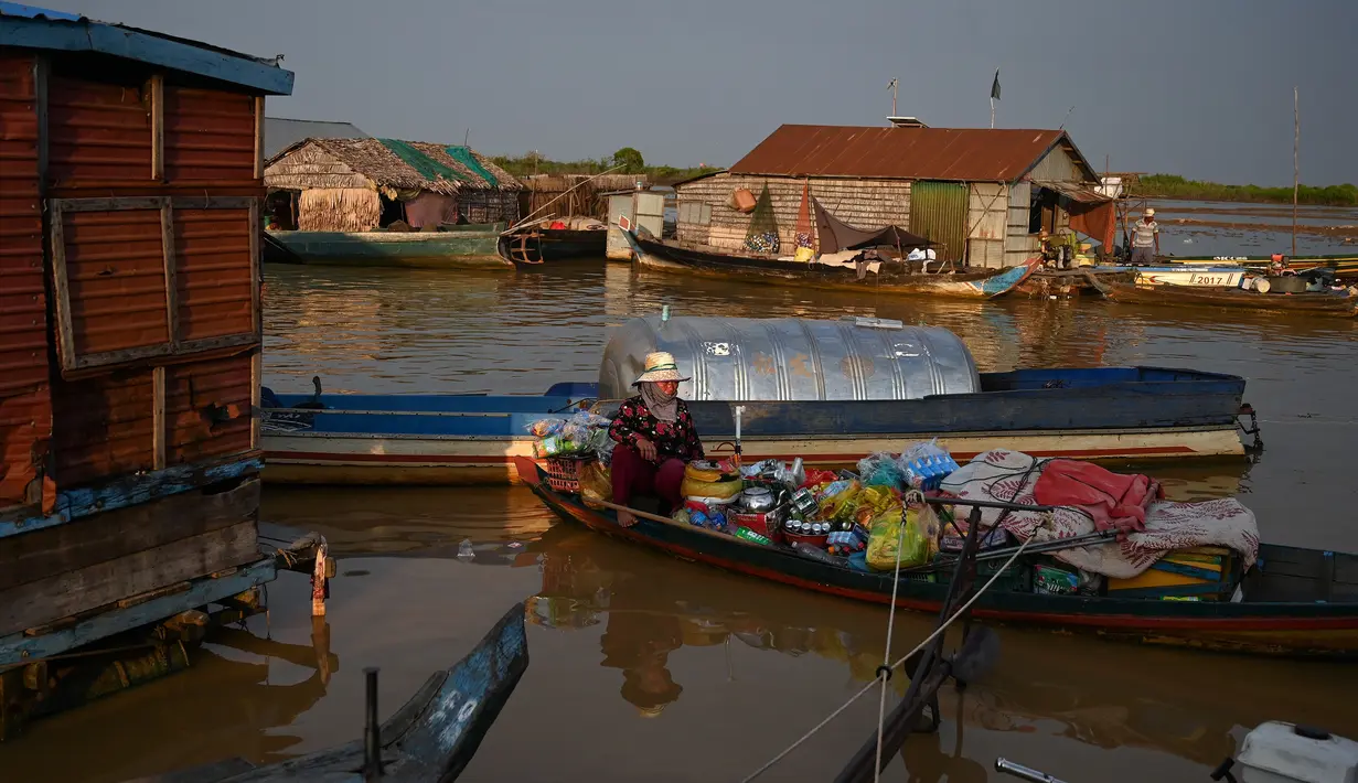 Seorang wanita menjual barang di atas kapal di sebuah desa terapung di sepanjang sungai Siem Reap Kamboja (5/12/2019). Desa Terapung Siem Reap adalah pintu gerbang ke danau air tawar terbesar di Asia Tenggara-Danau Tonle Sap. (AFP/Manan Vatsyayana)