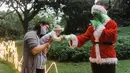 <p>Alexi Wright, 6 bulan (tengah) menjangkau Grinch berpakaian sebagai Santa Claus sementara ibunya, Kerrin (kiri), melihat selama kunjungan ke "Trail of Lights" Kebun Raya Durban menjelang Natal di Durban, Afrika Selatan (14/12/2021). (AFP/Rajesh Jayantilal)</p>