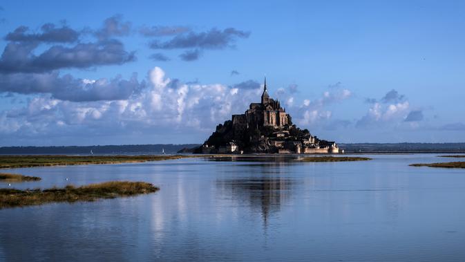 Kastil Mont Saint-Michel terlihat di Normandia, Prancis barat laut (1/9/2019). Dahulu Mont Saint Michel awalnya terhubung dengan daratan utama melalui sebuah jembatan kecil. Namun pada saat pasang jembatan tersebut tertutup dan terlihat pada saat surut. (AFP Photo/Joel Saget)