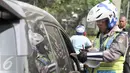 Petugas menilang pengendara mobil yang melanggar aturan pembatasan kendaraan sistem ganjil genap di kawasan Sudirman, Jakarta, Selasa (30/8). Hari ini resmi diberlakukan denda bagi pelanggar aturan sistem ganjil genap. (Liputan6.com/Yoppy Renato)