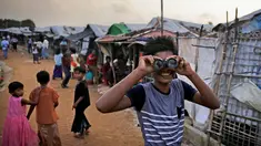 Seorang bocah Rohingya melihat melalui teropong mainan pada perayaan Idul Adha di kamp pengungsi Kutupalong, Bangladesh, Rabu (22/8). Hampir setahun mereka menghuni kamp ini usai kabur menghindari represi militer di Negara Bagian Rakhine. (AP/Altaf Qadri)