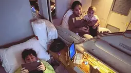 Di dalam pesawat, Rafathar tak bisa tidur. Ia pun memilih bermain gadget kesayangannya. (Foto: Instagram/@chevirgo)