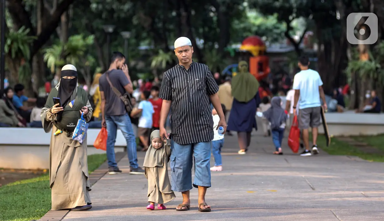 Warga jalan-jalan saat berkunjung ke Lapangan Banteng, Jakarta Pusat, Minggu (19/6/2022). Sejak kembali dibuka usai pandemi COVID-19 mereda, Lapangan Banteng kian ramai didatangi warga Jakarta dan menjadi salah satu lokasi wisata alternatif untuk menghabiskan waktu bersama keluarga serta sarana olahraga. (merdeka.com/Iqbal S. Nugroho)