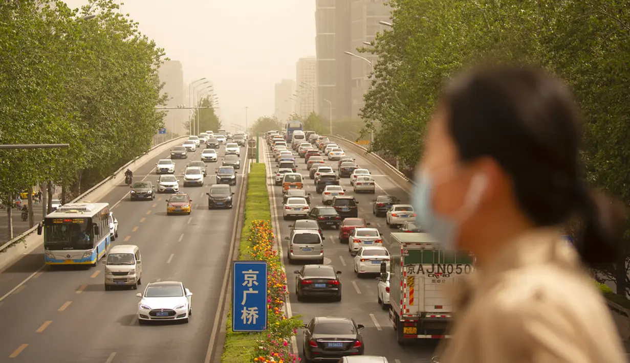 Seorang wanita yang memakai masker wajah berjalan melintasi jembatan penyeberangan saat badai pasir di Beijing, China, Kamis (6/5/2021). Debu dan badai pasir akhir musim semi mengirim indeks kualitas udara melonjak di Ibu Kota China pada hari ini. (AP Photo/Mark Schiefelbein)