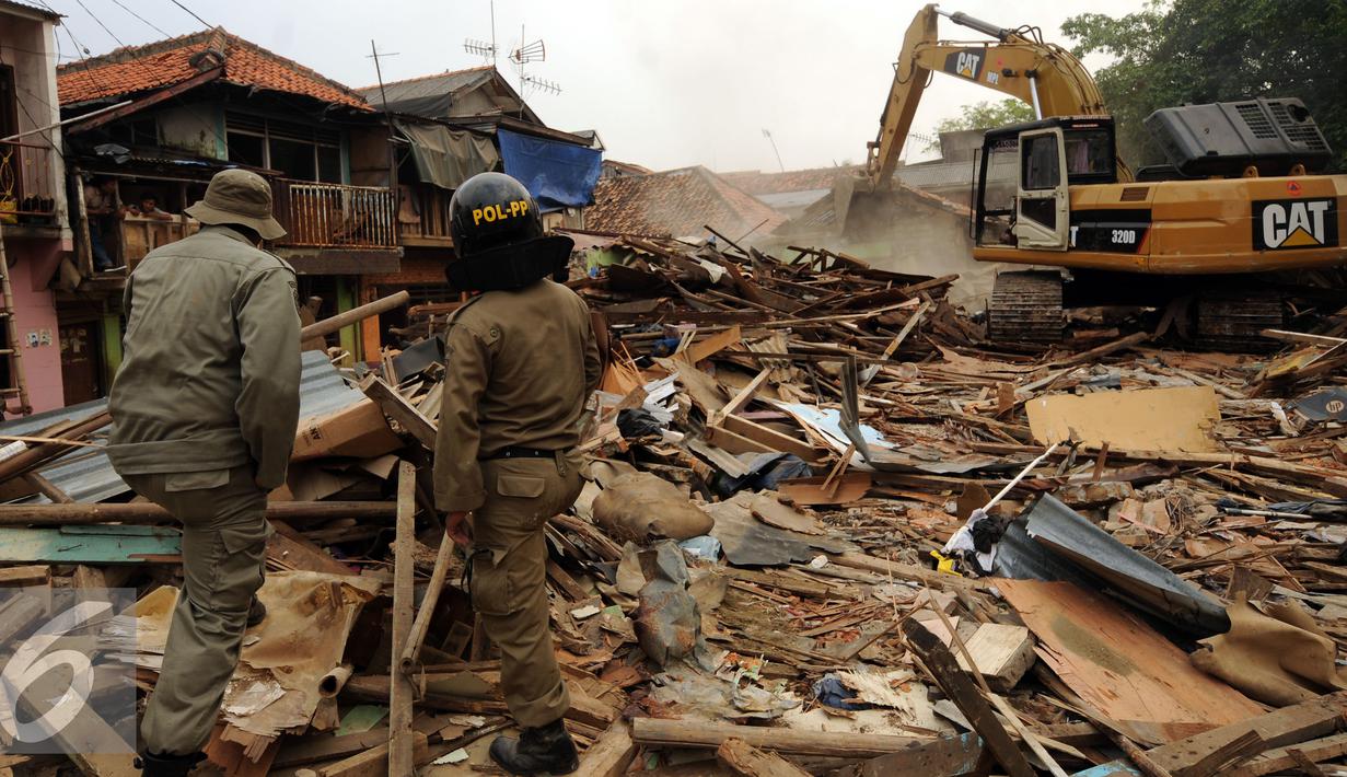 Petugas Satpol PP mengawasi proses pembongkaran rumah warga di Kampung Pulo, Jakarta, Kamis (20/8/2015). 2200 personil gabungan dari Kepolisian dan Satpol PP dikerahkan untuk mengamankan penggusuran tersebut. (Liputan6.com/Helmi Fithriansyah)