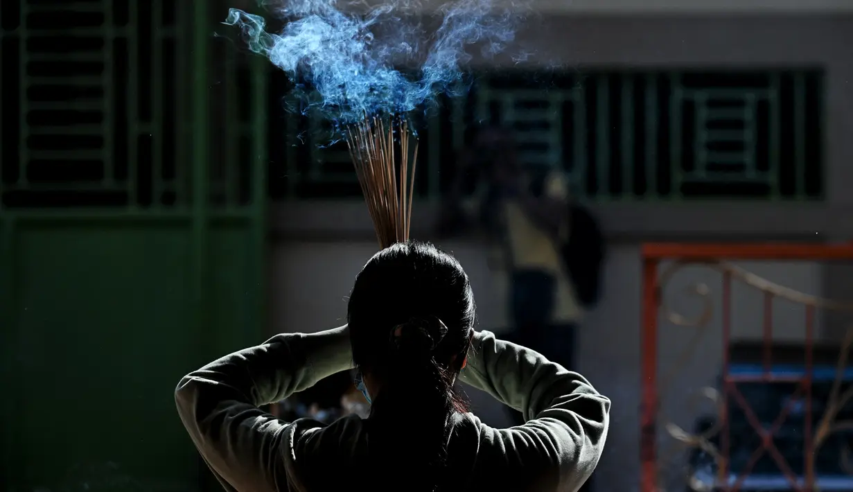 Seorang perempuan berdoa sambil memegang dupa di sebuah kuil Cina untuk menandai dimulainya Tahun Baru Imlek di Banda Aceh pada 1 Februari 2022. (CHAIDEER MAHYUDDIN / AFP)