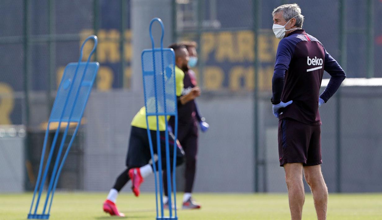 Pelatih Barcelona, Quique Setien, memperhatikan pemainnya saat sesi latihan di Ciutat Esportiva Joan Gamper, Sant Joan Despi, Jumat (8/5/2020) waktu setempat. Barcelona kembali menjalani latihan usai seluruh pemain tim utama dinyatakan negatif COVID-19. (AFP/Miguel Ruiz)