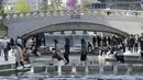 Orang-orang yang memakai masker menyeberangi Sungai Cheonggye di Seoul, Korea Selatan, Jumat (15/4/2022). Korea Selatan atau Korsel akan menghapus sebagian besar pembatasan pandemi covid-19, termasuk batas berkumpul di dalam ruangan, mulai 18 April 2022. (AP Photo/Ahn Young-joon)