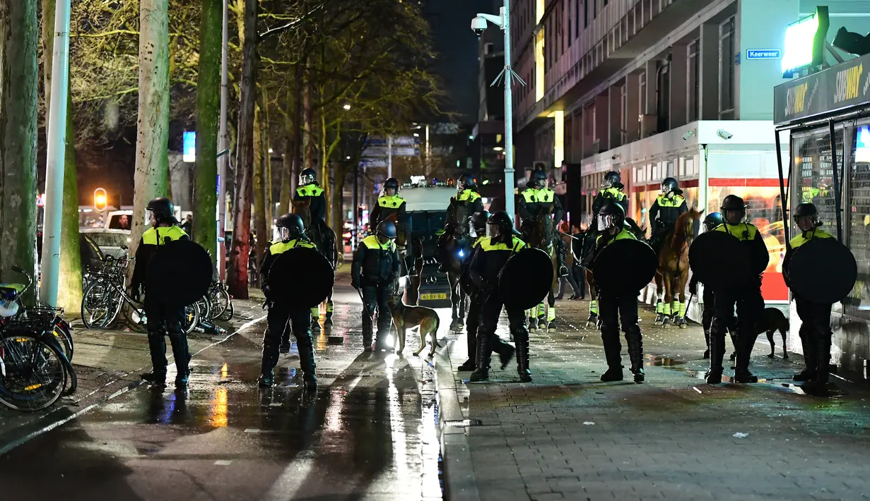 Polisi berusaha mengamankan aksi protes yang digelar oleh warga Turki di Rotterdam, Belanda (11/3). Mengetahui menterinya dilarang mendarat, Presiden Erdogan mendeskripsikan pemerintah Belanda adalah 'sisa Nazi dan fasis'. (AFP/Emmanuel Dunand)