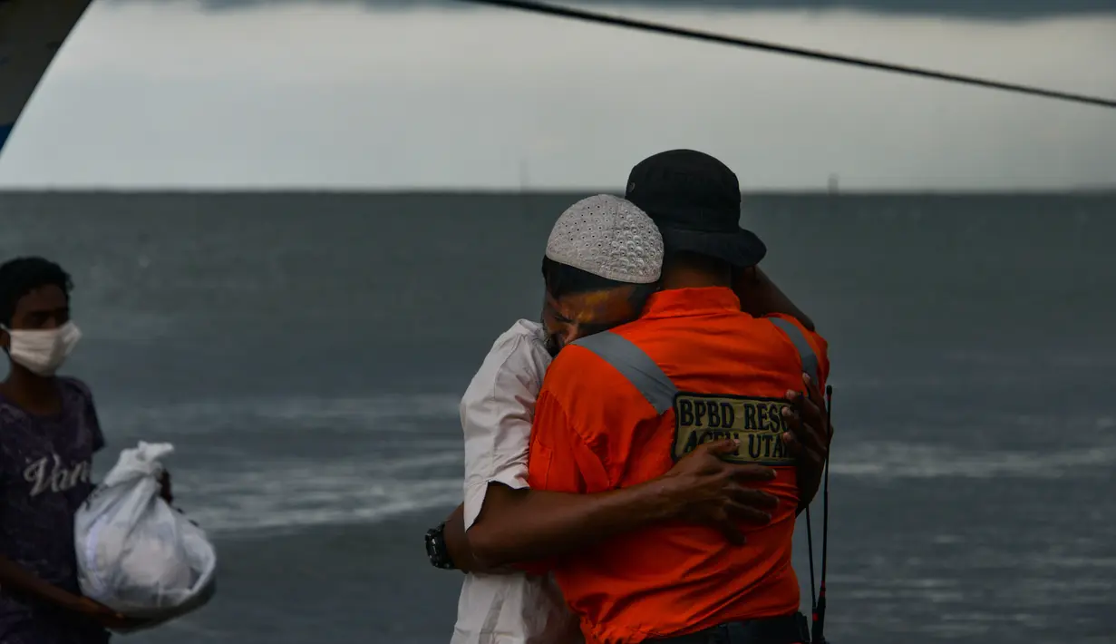 Seorang pria pengungsi etnis Rohingya memeluk petugas setelah dievakuasi di pesisir pantai Lancok, di Kabupaten Aceh Utara, Kamis (25/6/2020). Hampir 100 orang etnis Rohingya, termasuk 30 orang anak-anak ditemukan terdampar di tengah laut dengan kondisi kapal rusak. (CHAIDEER MAHYUDDIN/AFP)