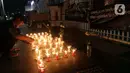 Seorang pencari suaka menyalakan lilin membentuk nama kota di Afghanistan saat aksi keprihatinan yang digelar di depan kantor UNHCR, Jakarta, Selasa (11/5/2021). Mereka prihatin atas peristiwa serangan bom yang menewaskan puluhan siswi di Kabul, Afghanistan. (Liputan6.com/Helmi Fithriansyah)