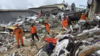 Tim penyelamat mencari korban di sebuah bangunan yang runtuh di kota Mamuju, Sulawesi Barat, Sabtu (16/1/2021). Jalan dan jembatan yang rusak, pemadaman listrik, dan kurangnya alat berat menghambat evakuasi setelah gempa bermagnitudo 6,2 SR yang melanda Majene- Mamuju. (Hariandi Hafid/AFP)
