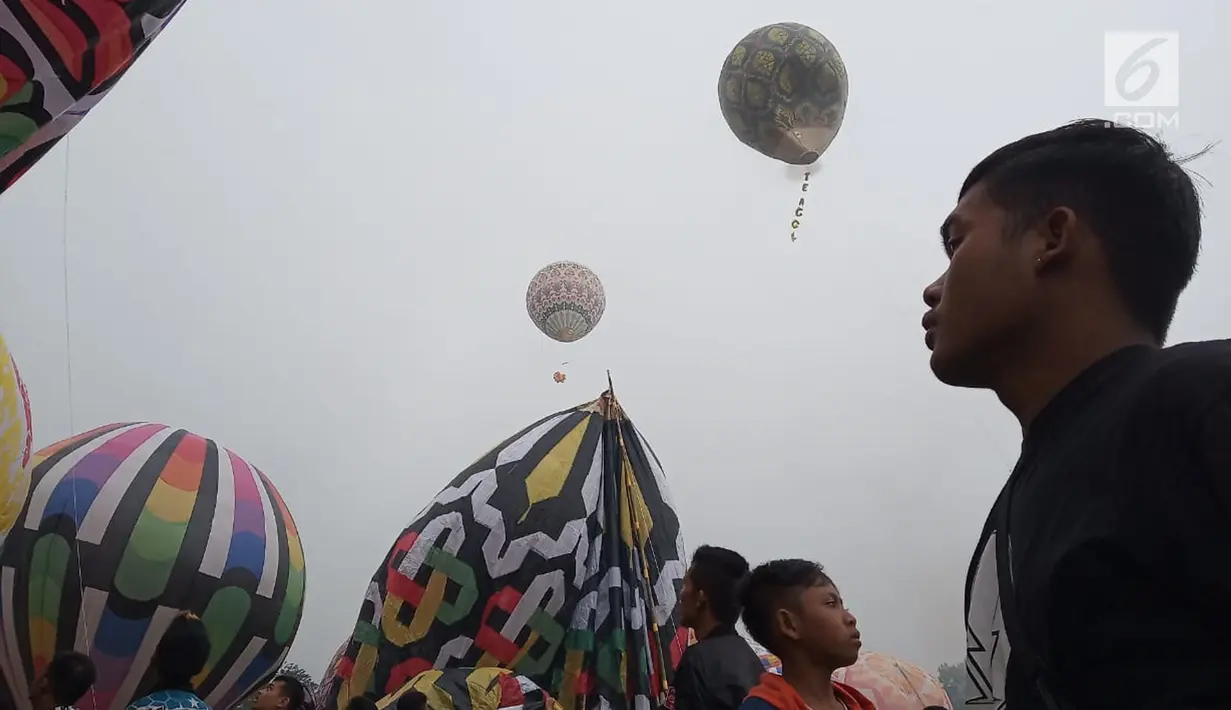 Seorang pria melihat balon udara dinaikan di Lapangan Pagerejo, Kertek, Kabupaten Wonosobo,  Sabtu (15/6/2019). Festival ini untuk memeriahkan syawalan dan wujud syukur warga yang hidup di lereng gunung sindoro dan sumbing. (Liputan6.com/Gholib)