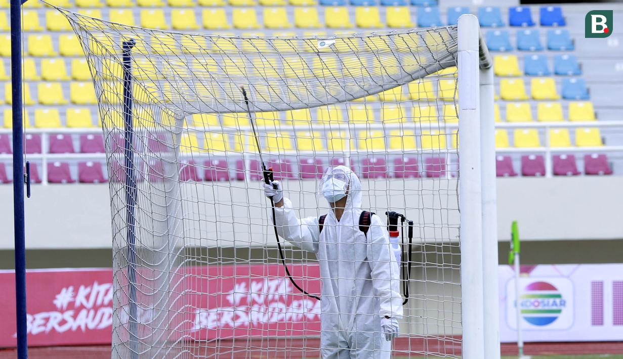 Petugas menyemprot jaring gawang dengan disinfektan sebelum pertandingan antara Persikabo 1973 melawan Arema FC pada laga Piala Menpora di Stadion Manahan, Solo, Minggu (21/3/2021). (Bola.com/M Iqbal Ichsan)