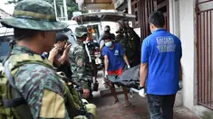 Personel polisi Filipina mengamati pekerja yang membawa jasad seorang napi yang tewas akibat kerusuhan di sebuah penjara di Filipina, Rabu (28/9). Selain menewaskan satu anggota geng narkoba, kerusuhan itu juga melukai tiga napi lainnya. (TED Aljibe/AFP)