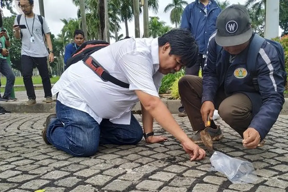 Petugas memperhatikan bekas aspal di Monas. (Merdeka.com/Yunita Amalia)