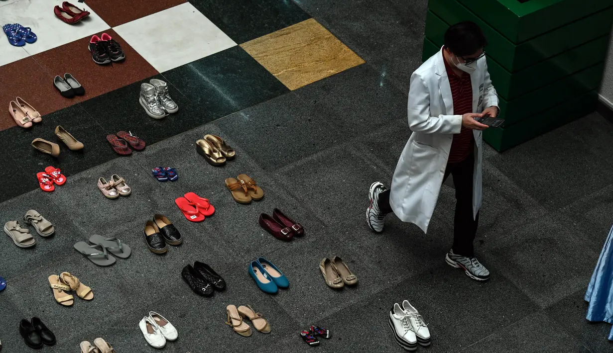 Seorang dokter berjalan di samping instalasi seni dengan 321 pasang sepatu yang menandakan kematian akibat merokok dalam rangka memperingati Hari Tanpa Tembakau Sedunia di Pusat Paru Filipina, Quezon City, pinggiran kota Manila, Filipina, Selasa (31/5/2022). (JAM STA ROSA/AFP)