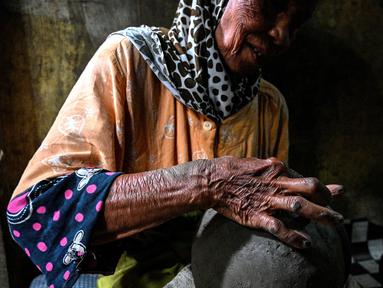 Seorang pembuat tembikar membuat pot tanah liat menggunakan tangan dalam bengkel rumah di Banda Aceh, Aceh, Rabu (4/8/2021). (CHAIDEER MAHYUDDIN/AFP)