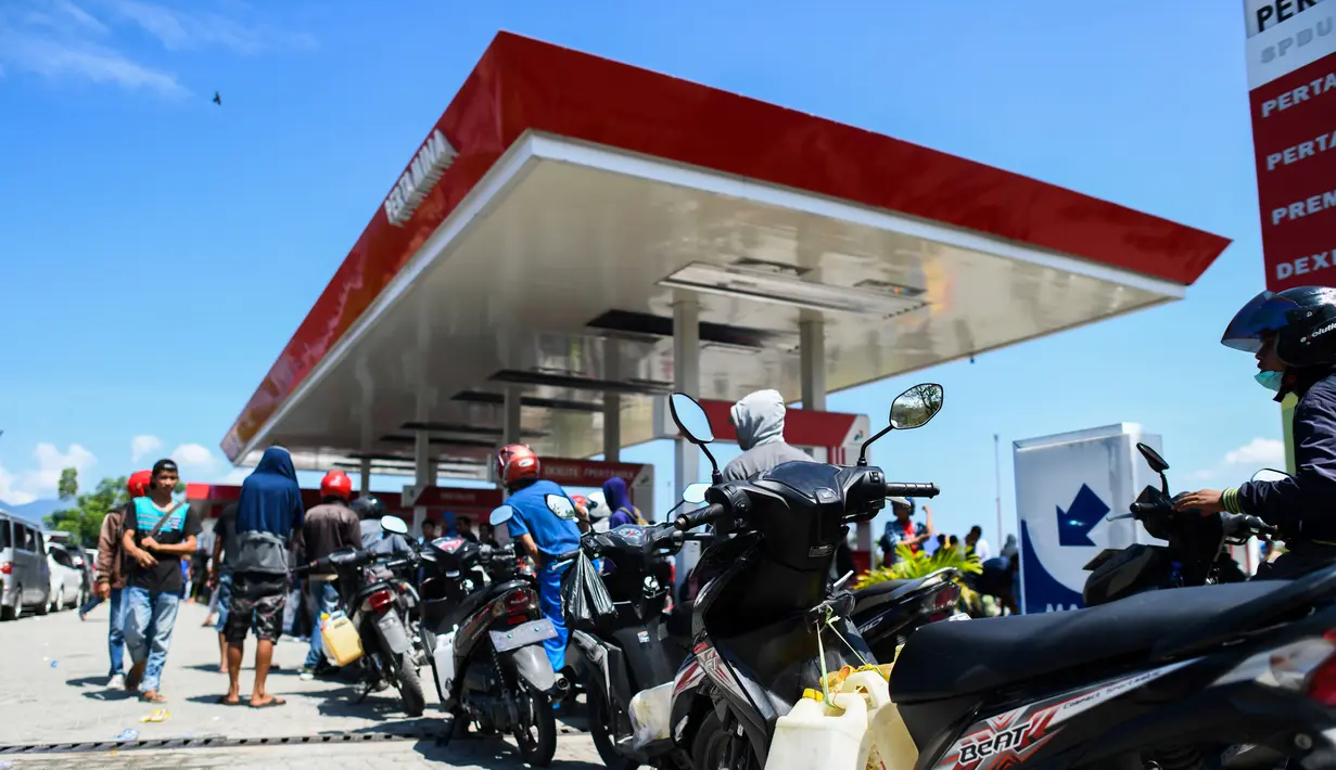 Pengendara sepeda motor mengantre untuk mendapatkan bahan bakar minyak (BBM) di SPBU Kota Palu, Sulawesi Tengah, Senin (1/10). Antrean bahkan mengular hingga ke jalan raya. (Jewel Samad/AFP)