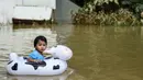 Seorang anak bermain saat banjir melanda kawasan Rantau Panjang, Malaysia, Kamis (5/1). Sekitar 23 ribu orang terpaksa mengungsi karena banjir yang disebabkan hujan muson ini. (AFP PHOTO / MOHD RASFAN)