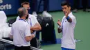 Petenis Serbia, Novak Djokovic berbicara dengan wasit setelah hantaman bolanya mengenai hakim garis saat kehilangan poin dari Pablo Carreno Busta (Spanyol) pada putaran keempat US Open 2020, di Flushing Meadows, (6/9/2020). Djokovic pun didiskualifikasi dari AS Terbuka 2020. (AP Photo/Seth Wenig)